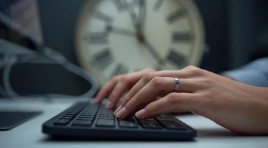 una immagine che mostri due mani che lavora al computer con lo sfondo di un orologio